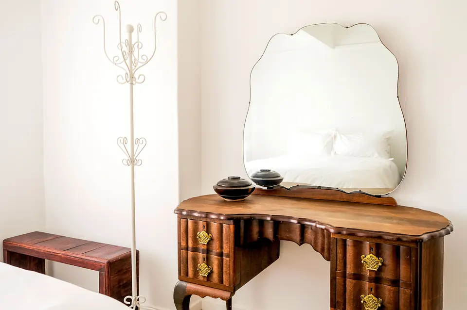 Antique kidney-shaped vanity and scalloped mirror in a guest bedroom