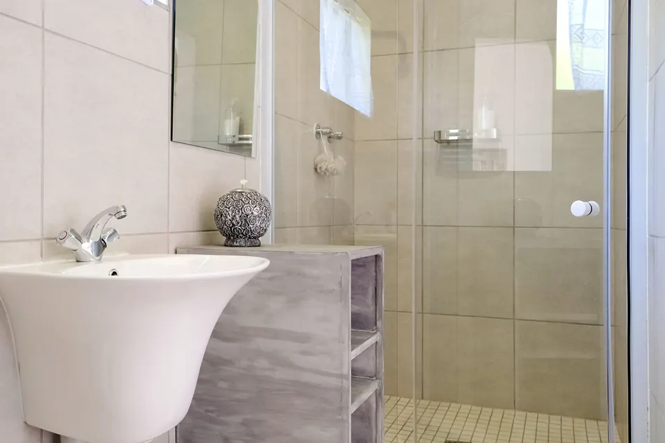 Bathroom with sculptural white basin, whitewashed vanity and glass shower