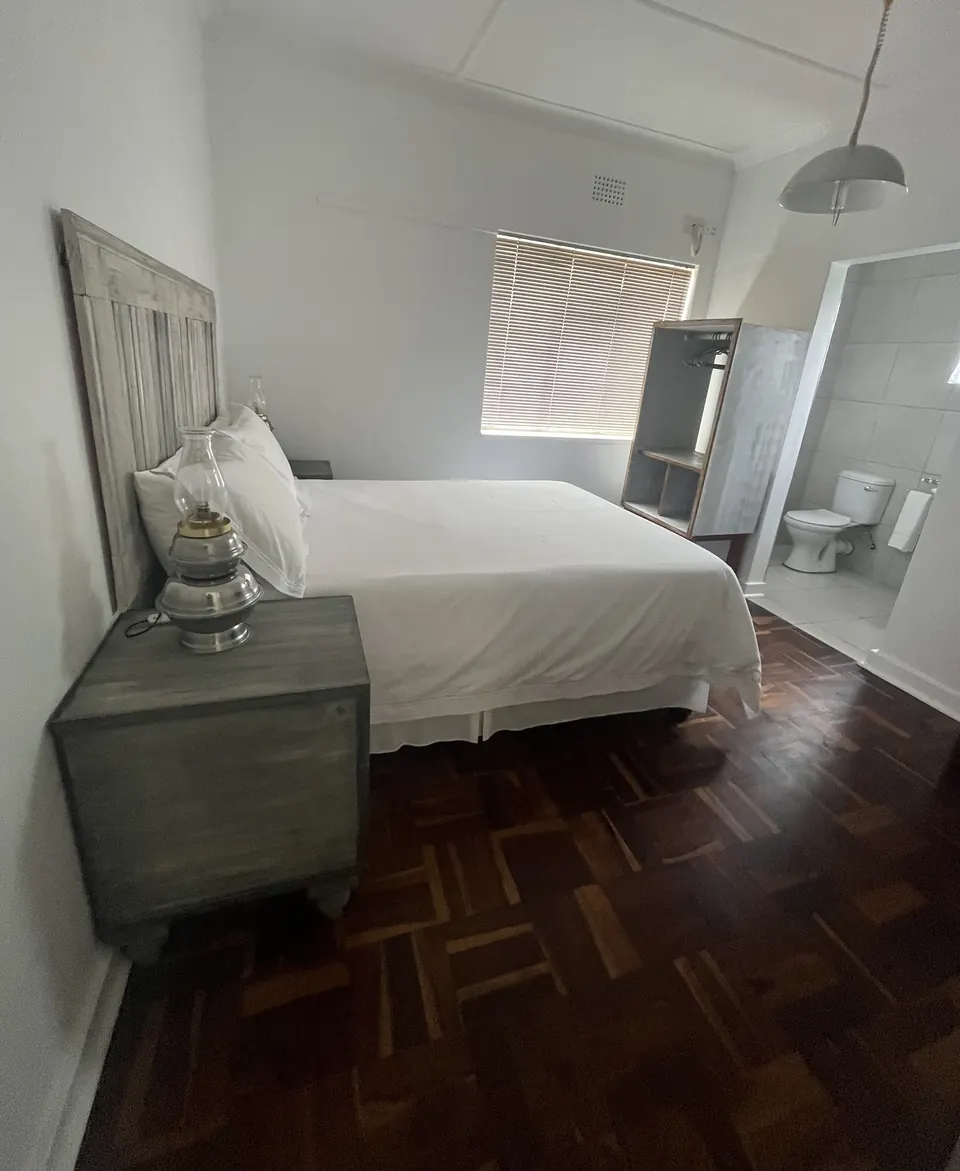 Double room with grey headboard and view through to the en-suite bathroom