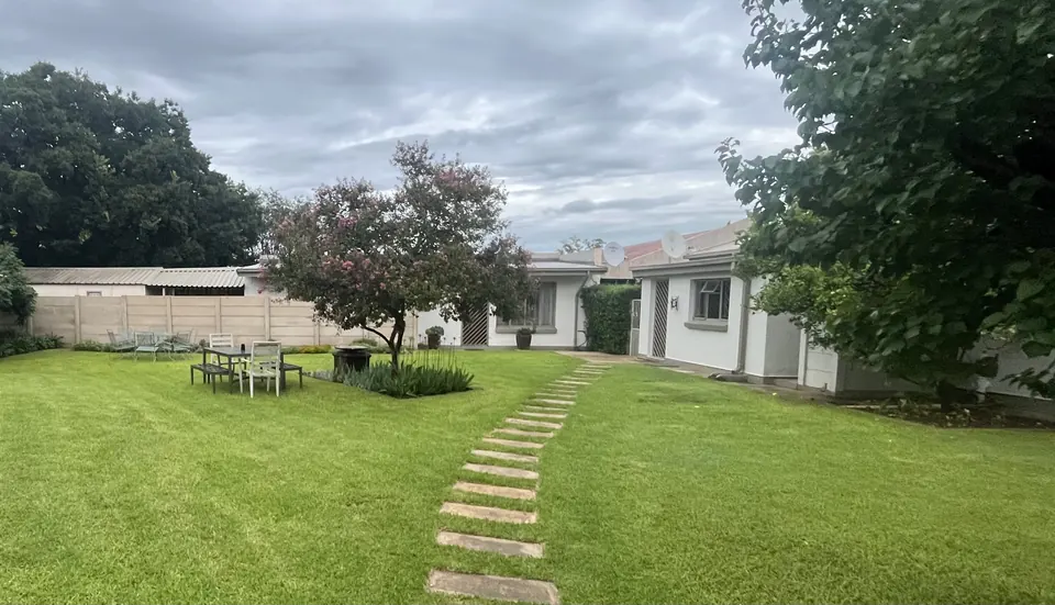 Green lawn with stepping-stone path, flowering tree and garden table