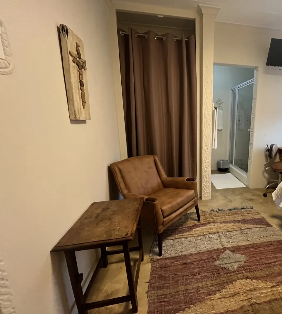 Handmade mosaic cross artwork above a leather armchair and woven rug