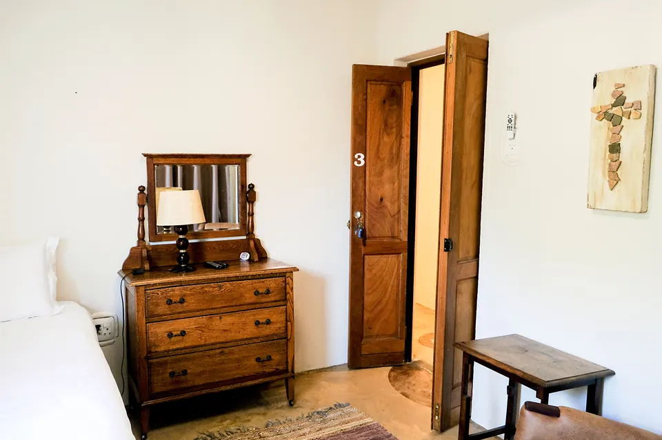 Guest room with antique dresser, table lamp and handmade mosaic cross