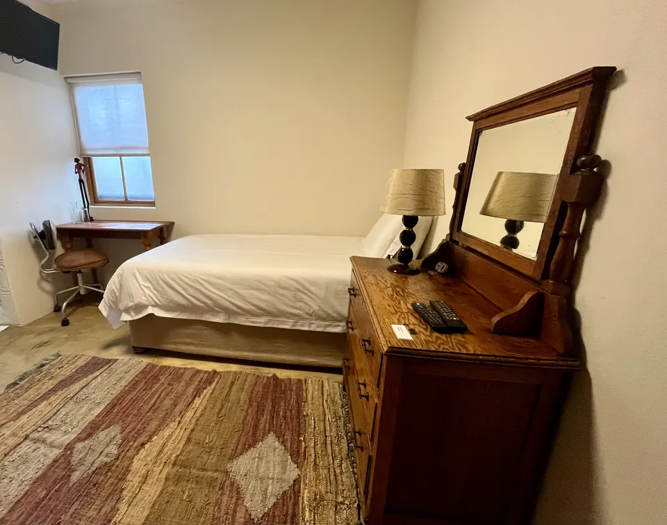 Single room with patterned rug, oak dresser and writing desk