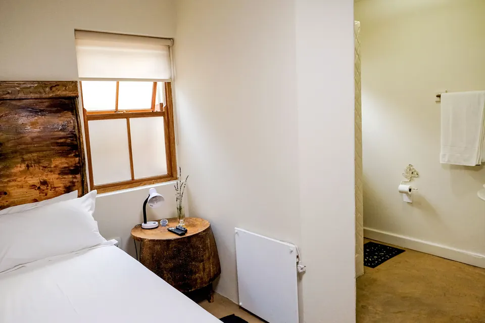 Single bed with reclaimed wooden headboard, tree-stump side table and en-suite bathroom