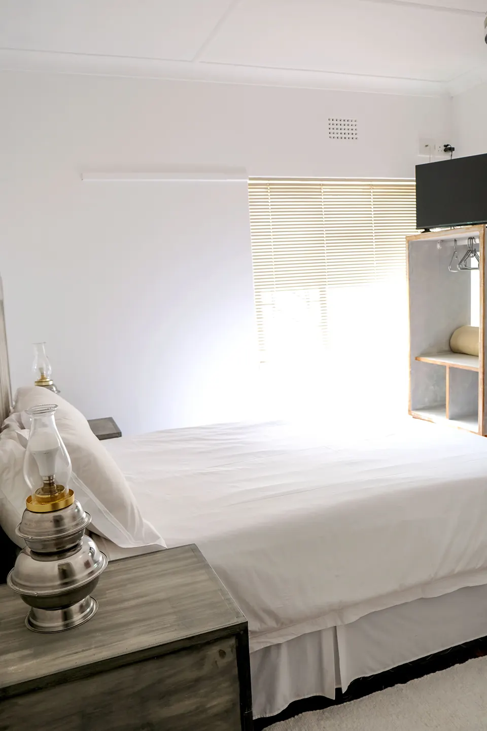 Bright guest room with white bedding and a brass oil lamp