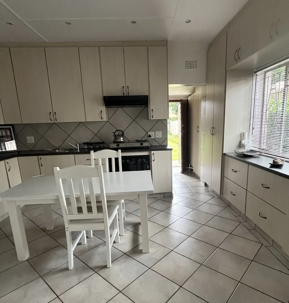 Fully fitted kitchen with window and white dining set