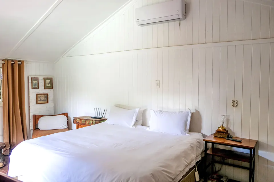 Wood-panelled double room with crisp white bedding, air-conditioning and vintage side table