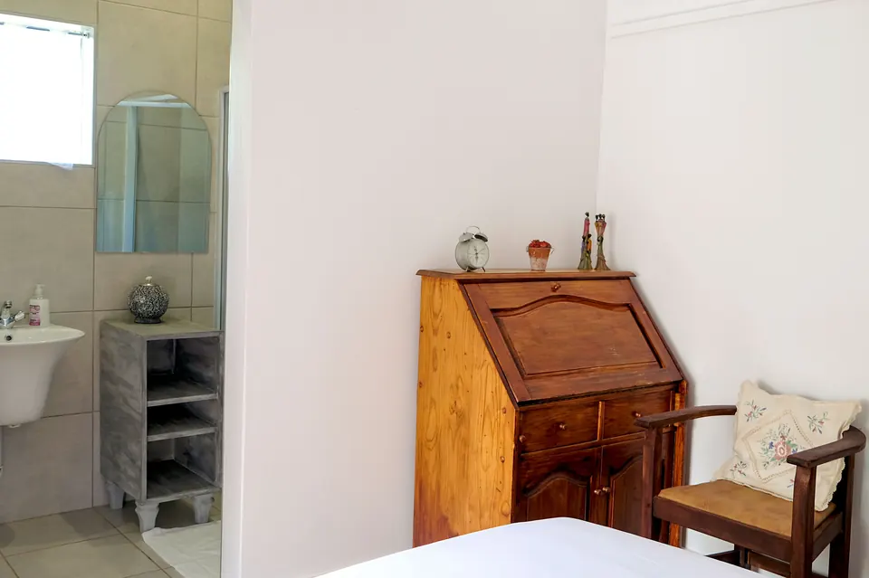 Antique writing bureau and embroidered chair beside an en-suite bathroom